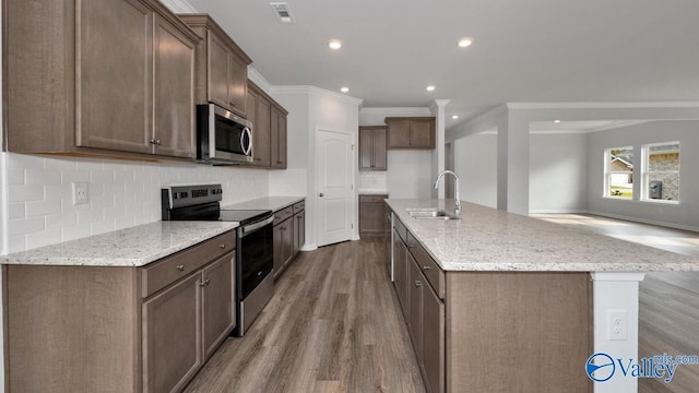 kitchen featuring light stone counters, sink, a center island with sink, and appliances with stainless steel finishes