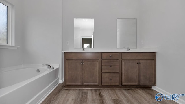 bathroom with wood-type flooring, a washtub, and vanity
