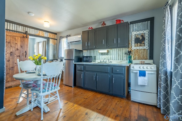 kitchen with a barn door, dark hardwood / wood-style flooring, white range, a wall mounted AC, and stainless steel fridge