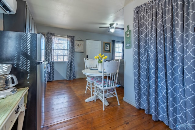 dining space featuring a wall unit AC, a healthy amount of sunlight, ceiling fan, and dark wood-type flooring