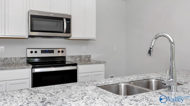 kitchen with appliances with stainless steel finishes, white cabinetry, and a sink