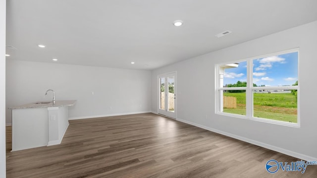 unfurnished living room with baseboards, visible vents, a sink, and dark wood-style flooring