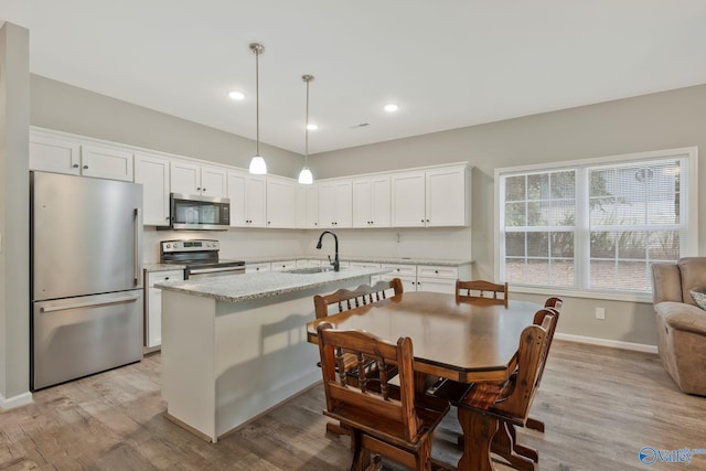 kitchen with stainless steel appliances, sink, white cabinetry, and light hardwood / wood-style floors