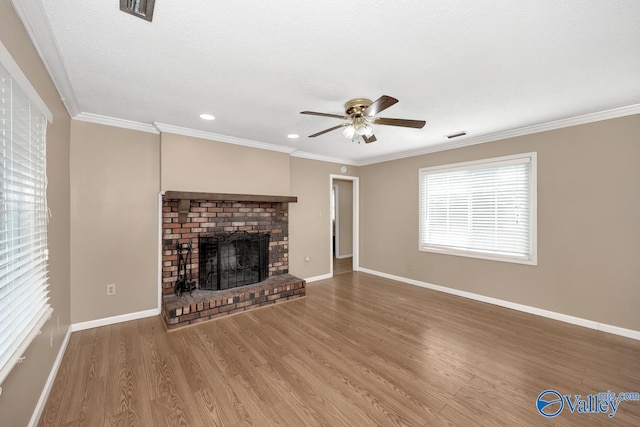 unfurnished living room featuring crown molding, a fireplace, a textured ceiling, hardwood / wood-style floors, and ceiling fan