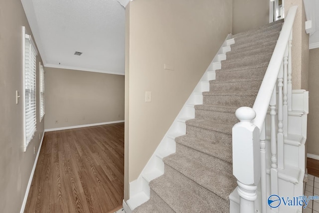 stairs featuring hardwood / wood-style flooring and crown molding