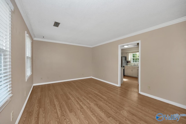 spare room with light hardwood / wood-style floors, a textured ceiling, and ornamental molding