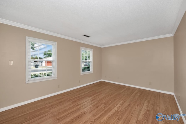 empty room with light wood-type flooring, a textured ceiling, and crown molding