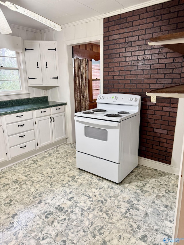 kitchen featuring white electric range oven, white cabinetry, crown molding, and brick wall