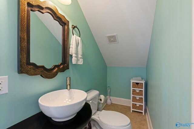 bathroom featuring tile patterned floors, sink, lofted ceiling, and toilet