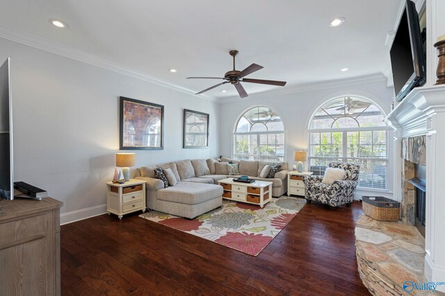 living room featuring ornamental molding, a fireplace, ceiling fan, and dark wood-type flooring