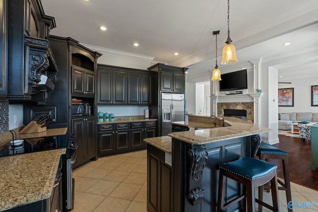 kitchen with pendant lighting, light stone countertops, a kitchen island, light hardwood / wood-style floors, and appliances with stainless steel finishes