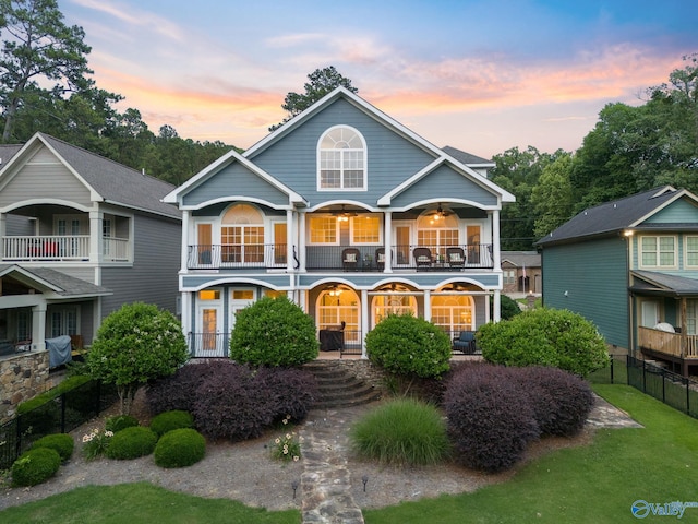 back house at dusk with a balcony and a porch