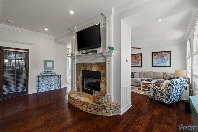 living room featuring a stone fireplace, crown molding, and wood-type flooring