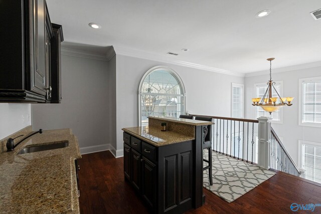 kitchen featuring dark wood-type flooring, a notable chandelier, a breakfast bar area, and sink