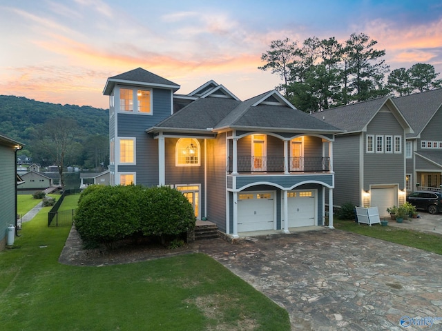 view of front of house with a balcony, a garage, and a lawn