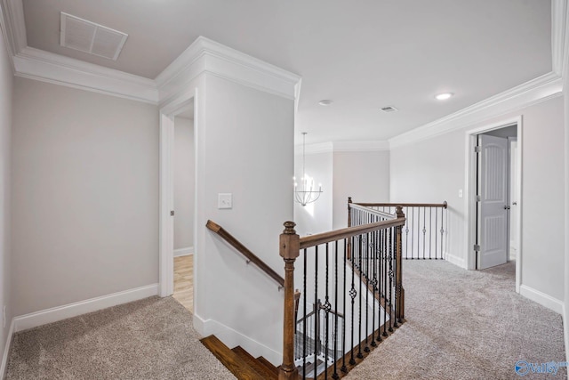 hall featuring crown molding, carpet floors, and an inviting chandelier