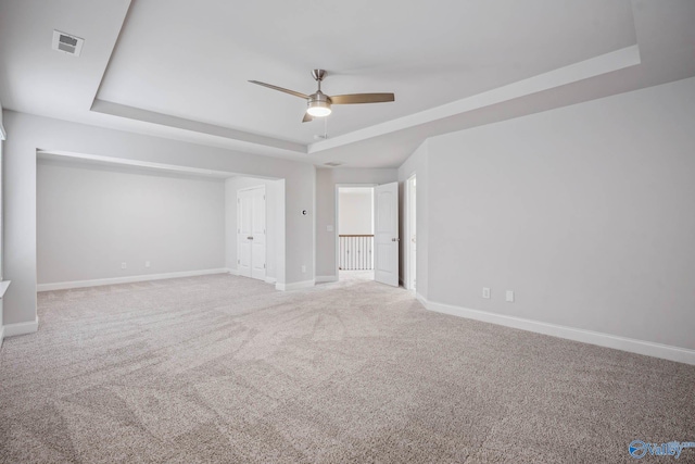 unfurnished room with ceiling fan, a raised ceiling, and carpet