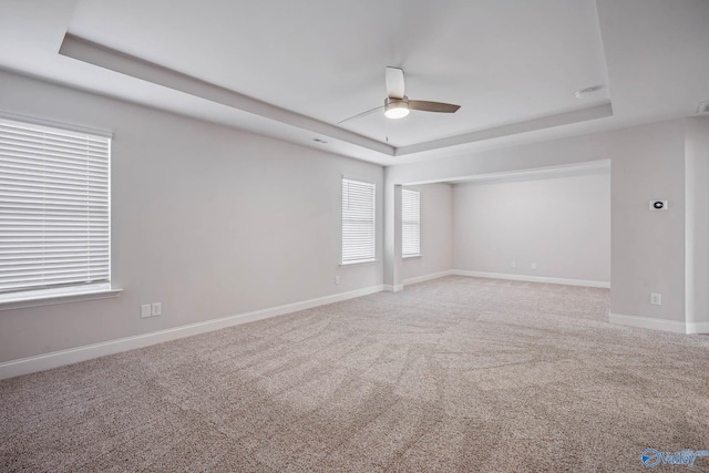 unfurnished room with ceiling fan, carpet flooring, and a raised ceiling