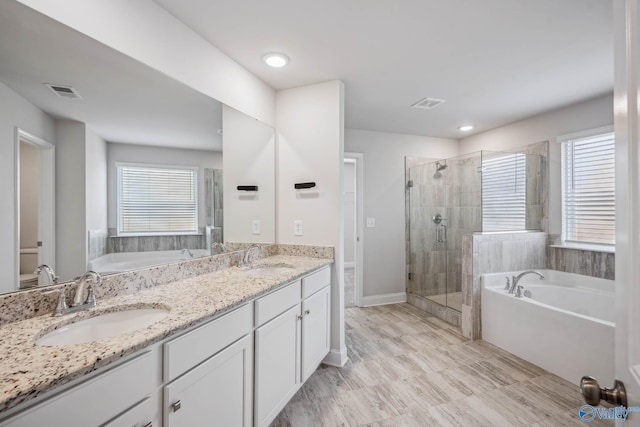 bathroom with vanity and shower with separate bathtub