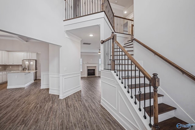 stairway with hardwood / wood-style flooring, ornamental molding, and a high ceiling