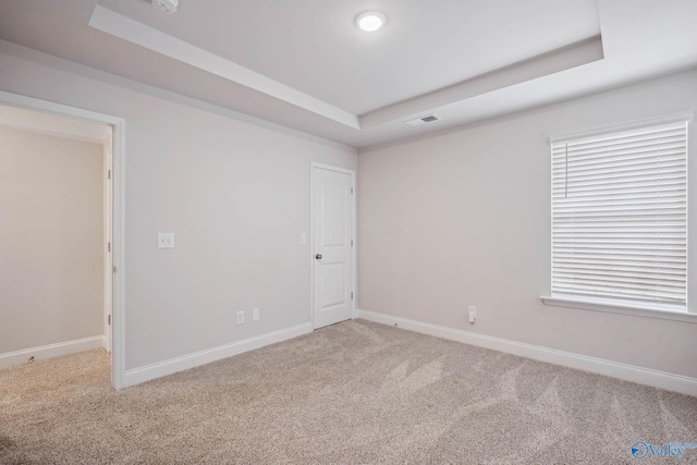 carpeted empty room featuring a raised ceiling