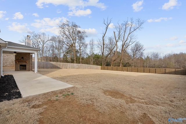 view of yard with exterior fireplace and a patio area