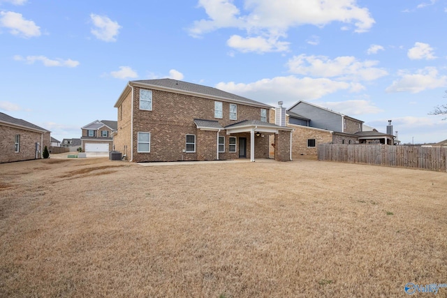 back of property with a garage, a yard, and cooling unit