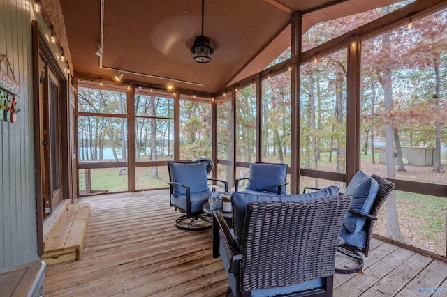 sunroom with a healthy amount of sunlight, a water view, lofted ceiling, and track lighting