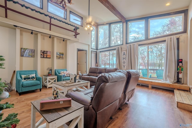 living room with ceiling fan, hardwood / wood-style floors, a towering ceiling, and beamed ceiling