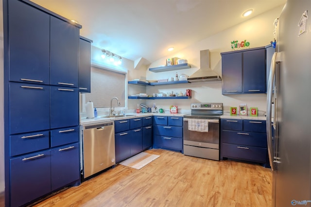 kitchen with lofted ceiling, sink, wall chimney exhaust hood, blue cabinetry, and appliances with stainless steel finishes