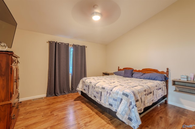 bedroom with light wood-type flooring, vaulted ceiling, and ceiling fan