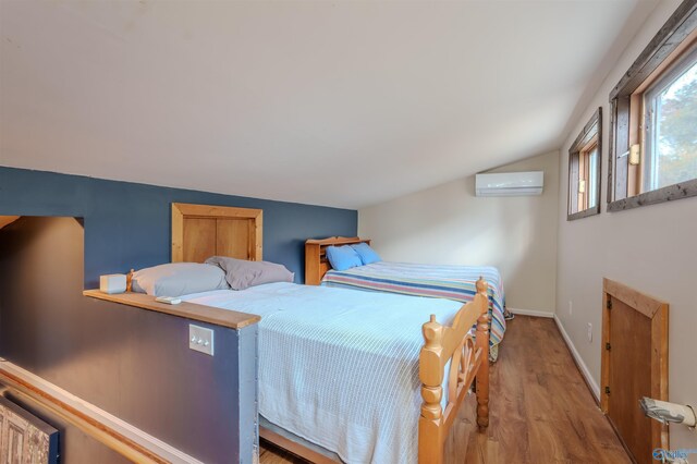 bedroom featuring a wall mounted air conditioner, vaulted ceiling, and light hardwood / wood-style flooring