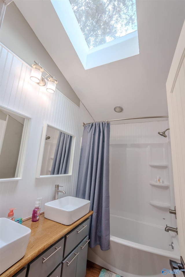 bathroom featuring vaulted ceiling with skylight, vanity, and shower / bath combination with curtain