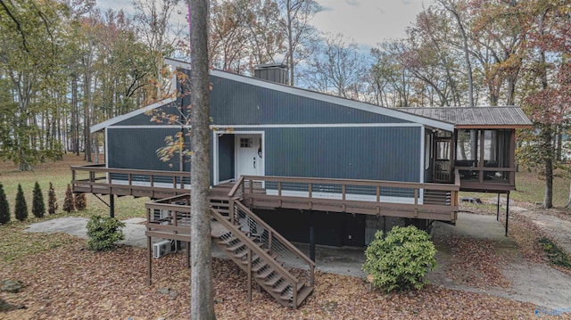 rear view of house featuring a wooden deck and a sunroom