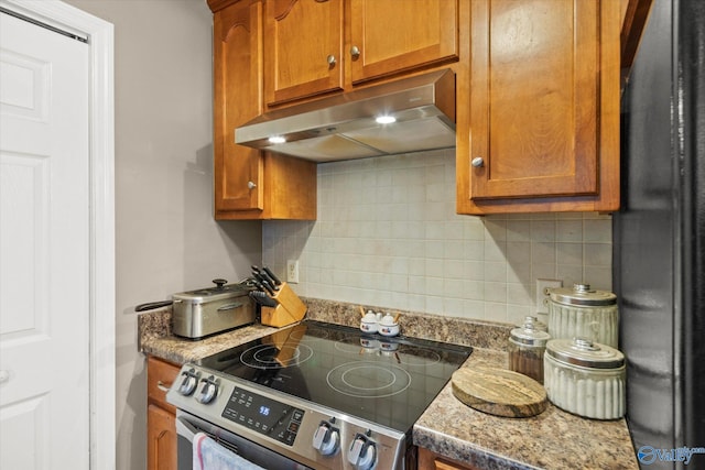 1004 Carter Grove Rd, Hazel Green, AL 35750 - kitchen with brown cabinetry, stainless steel range with electric stovetop, under cabinet range hood, and decorative backsplash