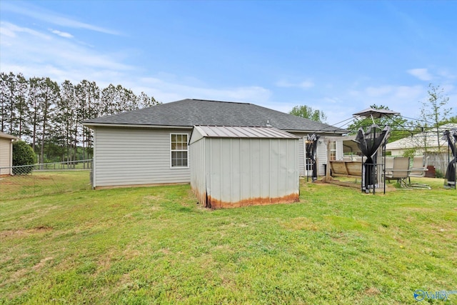 1004 Carter Grove Rd, Hazel Green, AL 35750 - rear view of house featuring an outdoor structure, fence, a storage shed, roof with shingles, and a lawn