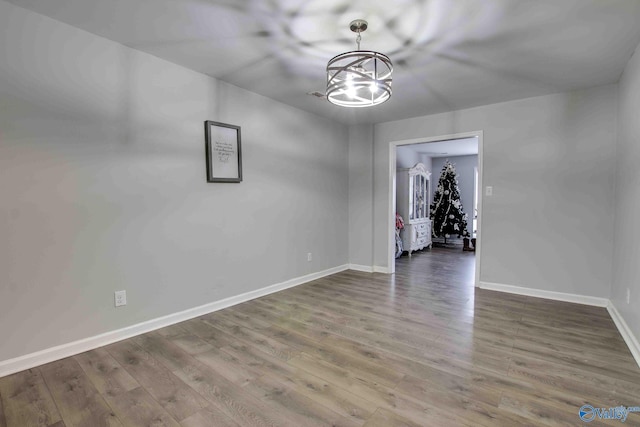 empty room with dark hardwood / wood-style floors and an inviting chandelier