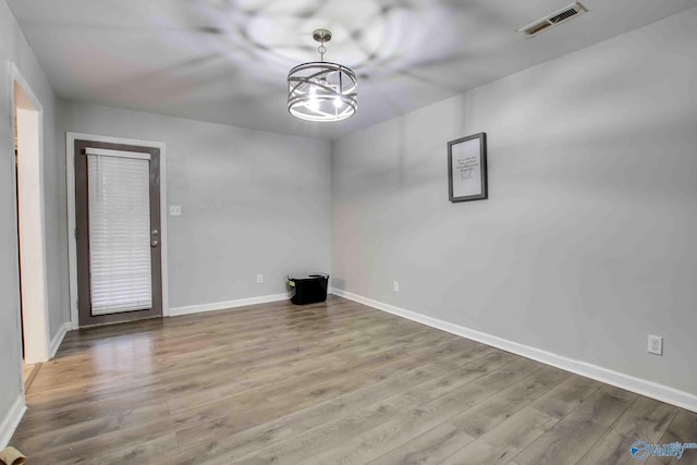 empty room featuring a chandelier and hardwood / wood-style floors