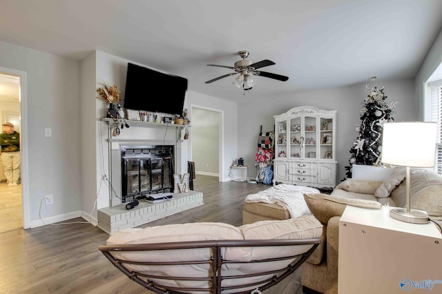 living room with ceiling fan, a fireplace, and dark wood-type flooring