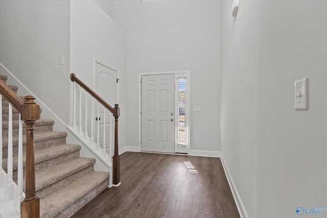 entrance foyer with a towering ceiling and dark wood-type flooring