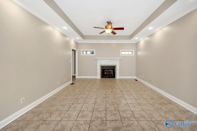 unfurnished living room with a tray ceiling, a ceiling fan, a tiled fireplace, and recessed lighting
