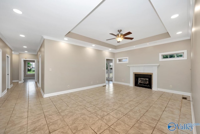 unfurnished living room featuring ornamental molding, a fireplace, a ceiling fan, light tile patterned floors, and a tray ceiling