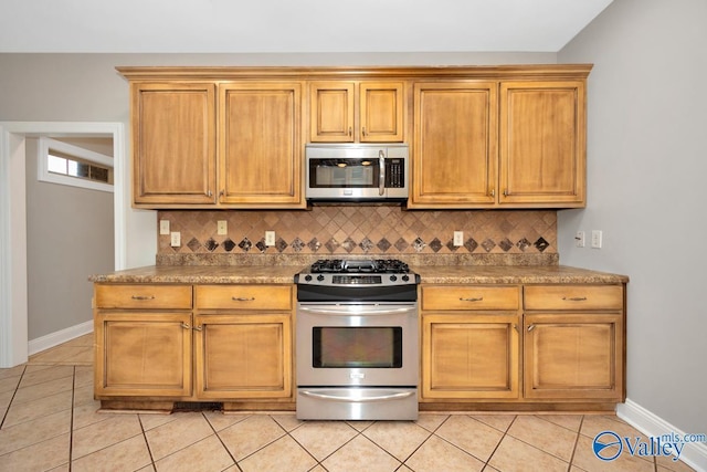 kitchen featuring stainless steel appliances, light tile patterned flooring, baseboards, and tasteful backsplash
