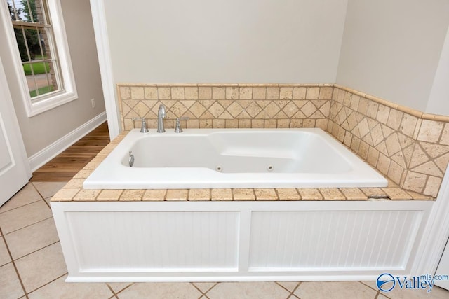 bathroom featuring a jetted tub, baseboards, and tile patterned floors