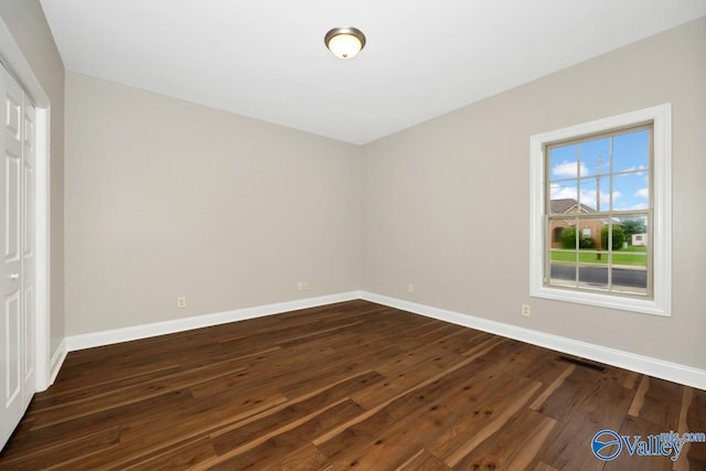 unfurnished bedroom featuring baseboards, dark wood-type flooring, visible vents, and a closet
