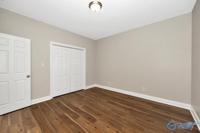 unfurnished bedroom featuring a closet, dark wood finished floors, and baseboards