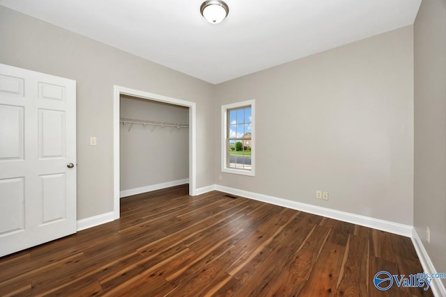 unfurnished bedroom featuring a closet, dark wood-type flooring, and baseboards
