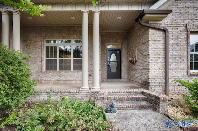 view of exterior entry featuring brick siding and covered porch