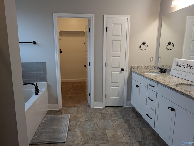 bathroom featuring a relaxing tiled tub and vanity