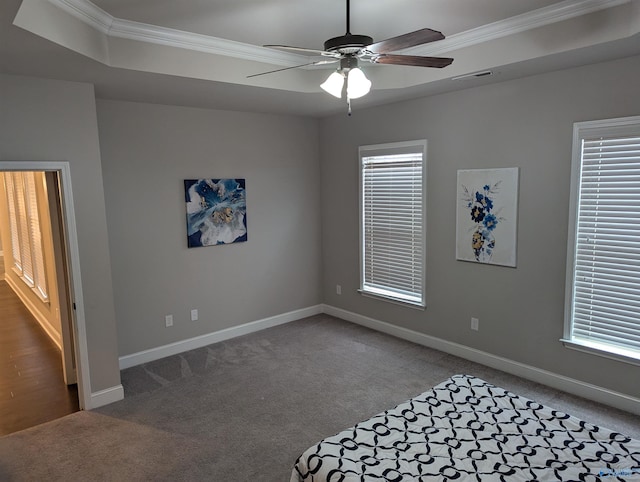 carpeted spare room featuring ceiling fan, crown molding, and a raised ceiling